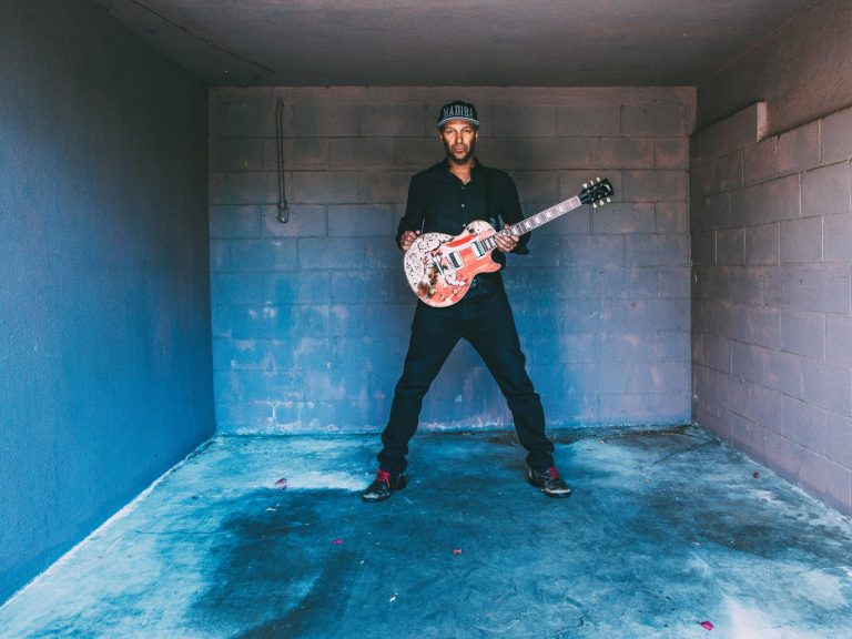 Musiker Tom Morello mit Gitarre in kleinem Raum